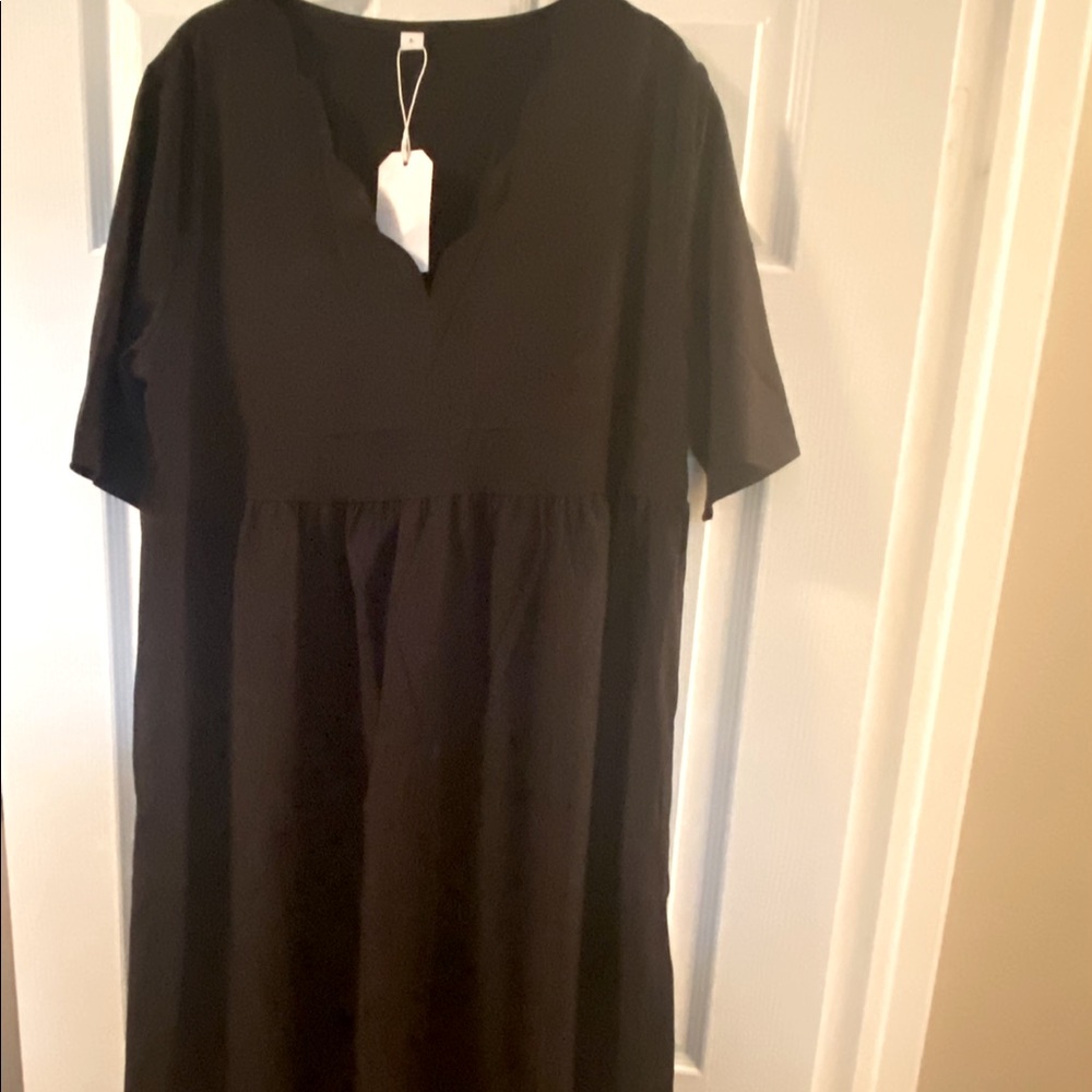 Women’s black short sleeve midi dress with pockets and scallop neckline.